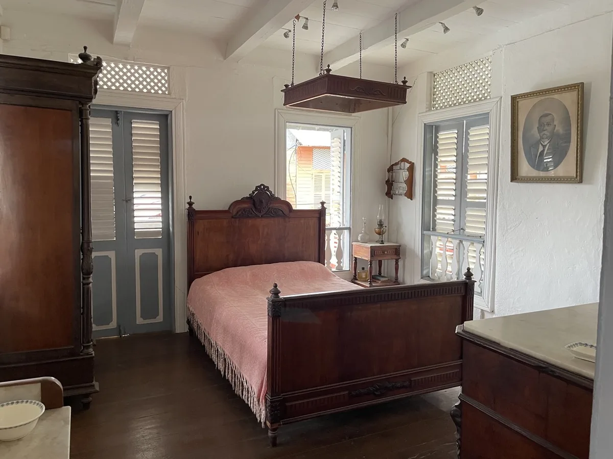 Chambre principale avec lit en bois sculpté et portrait d'Herménégilde Tell au mur
